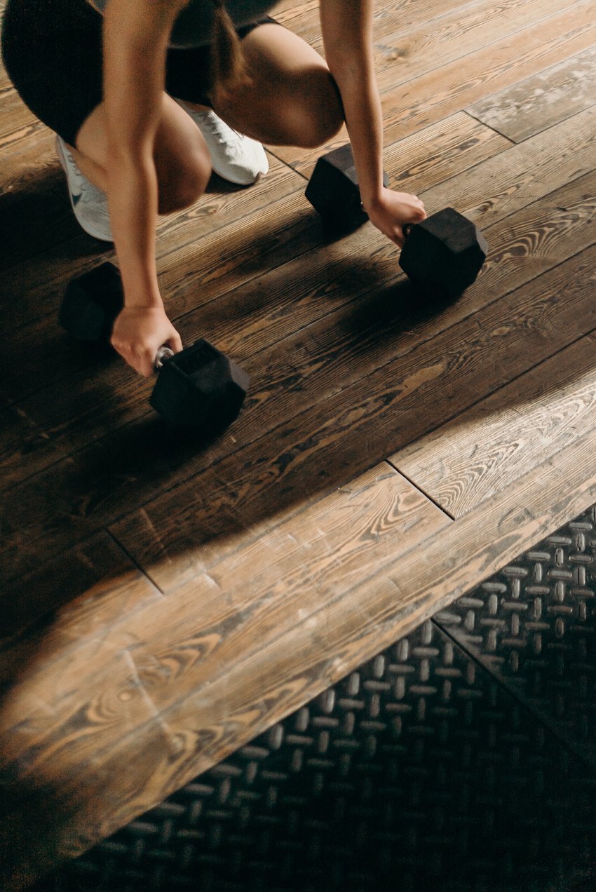 Person in White Shorts and Black Shoes Standing on Brown Wooden Floor